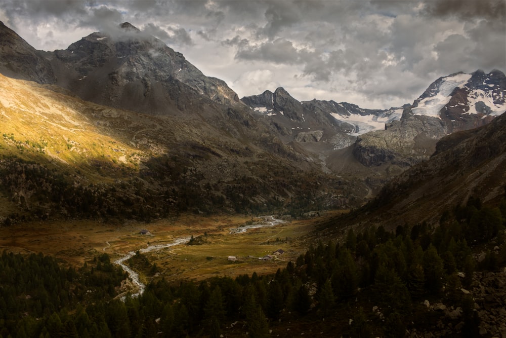 alberi verdi e montagne sotto il cielo nuvoloso durante il giorno