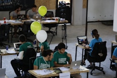 a group of people sitting at desks working on laptops