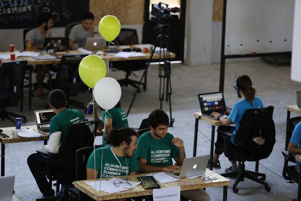 a group of people sitting at desks working on laptops