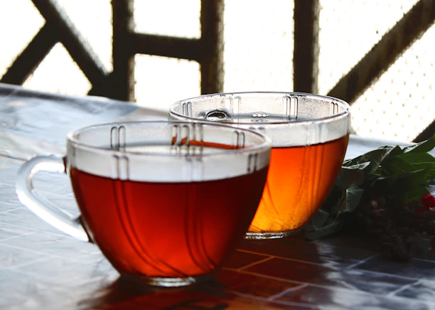 Close-up of traditional Moroccan tea being poured into ornate glasses on a vibrant patterned cloth.