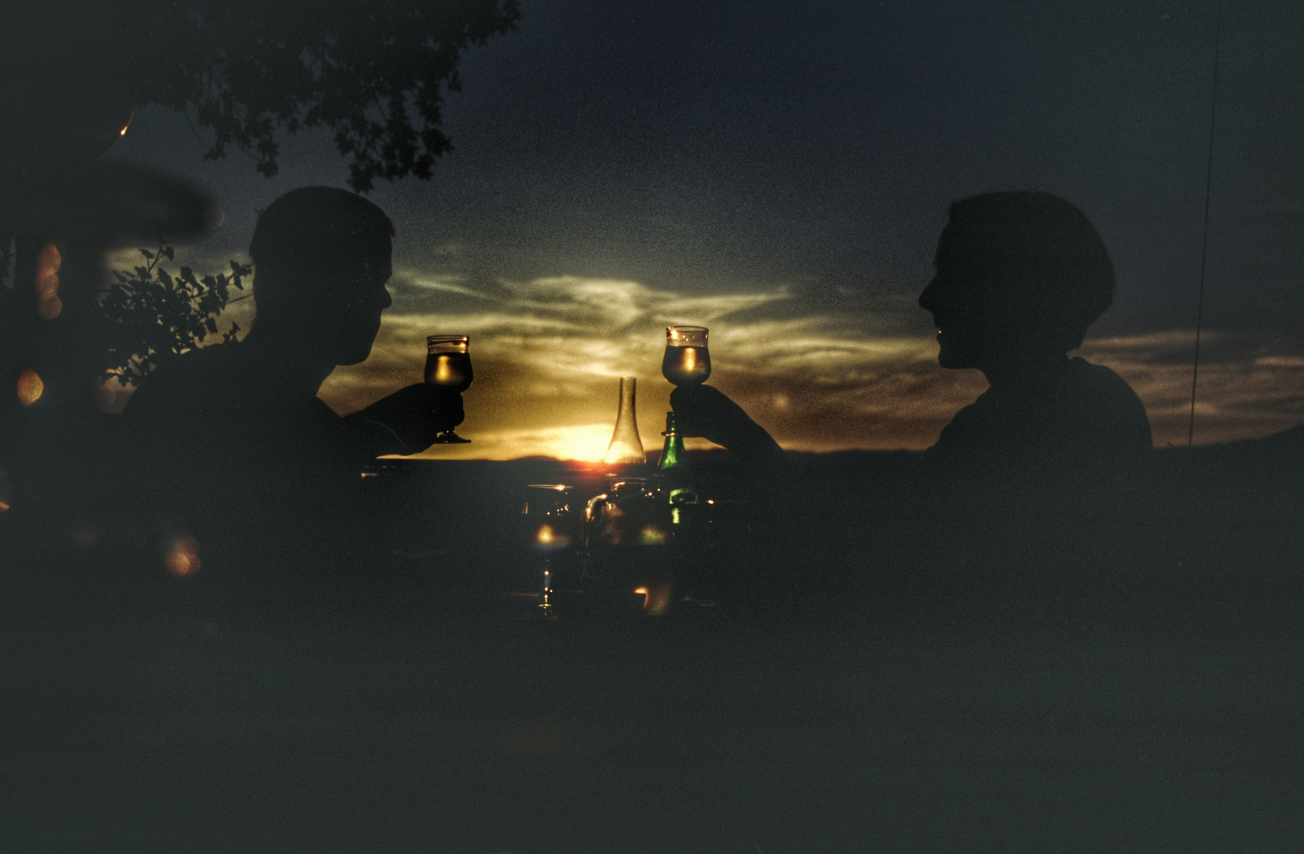 silhouette of man and woman sitting on ground with lighted candles during night time