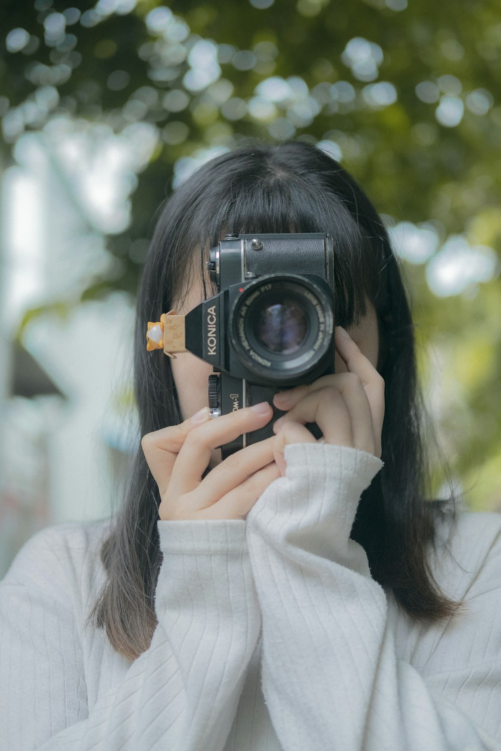 woman in white long sleeve shirt holding black and silver camera