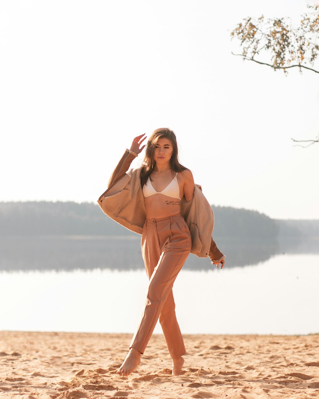 woman in brown long sleeve dress standing on brown sand near body of water during daytime