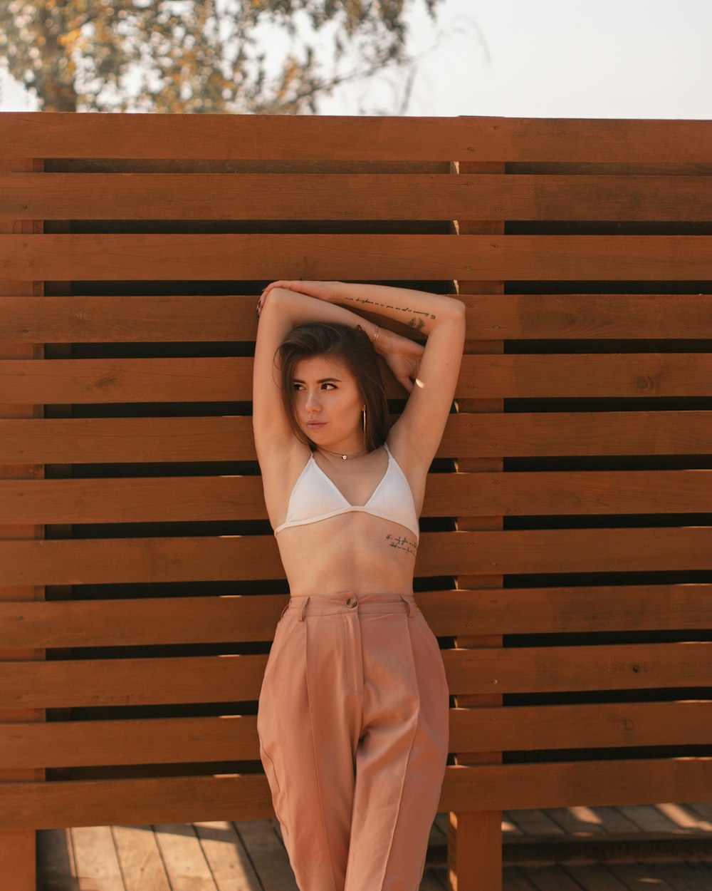 Femme en robe orange debout à côté d’un mur en bois brun