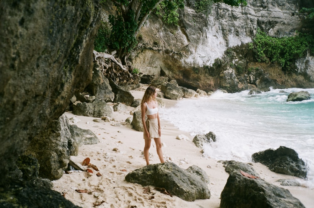 woman in white dress walking on beach during daytime