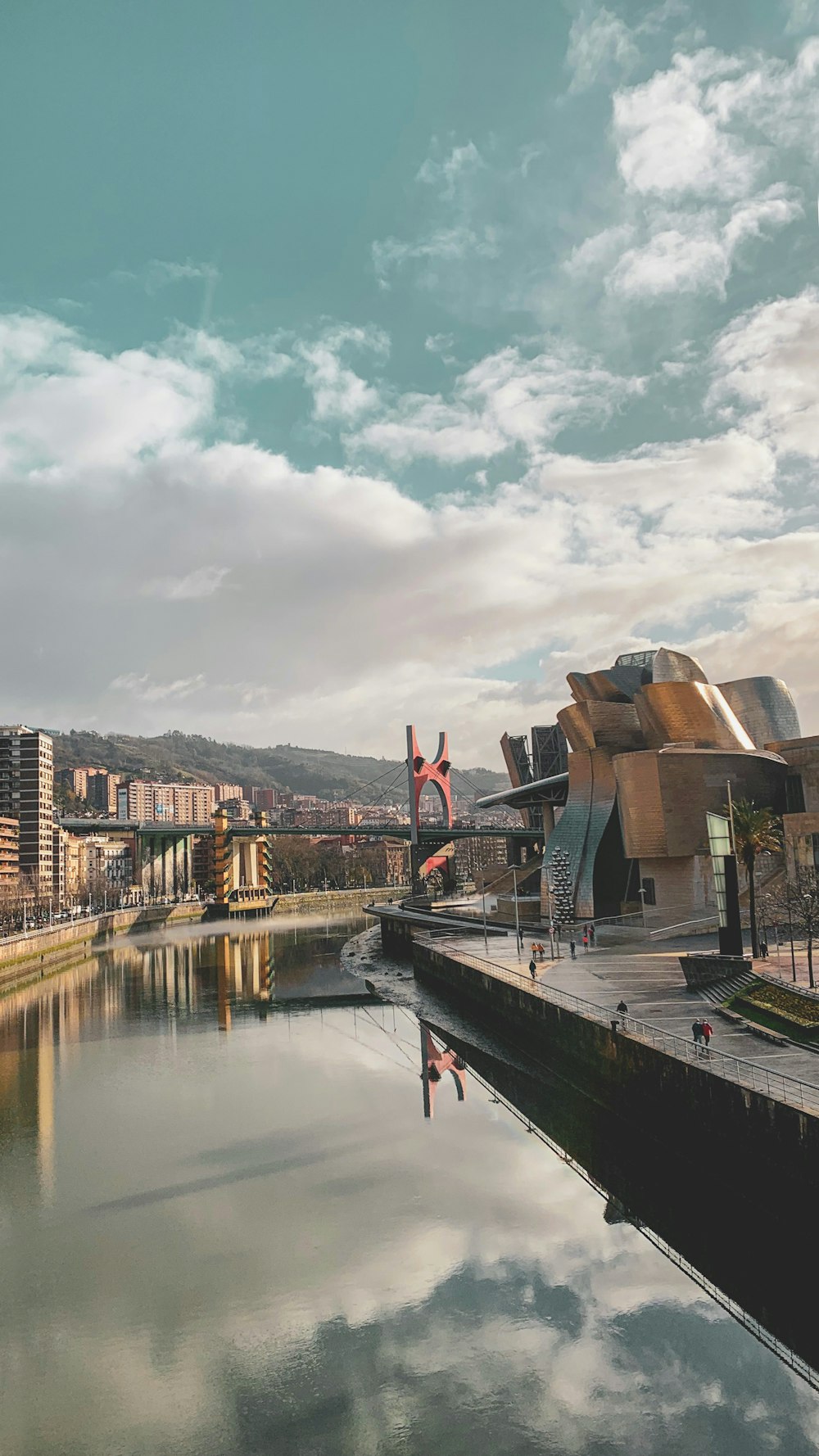 brown and white concrete buildings near body of water under white clouds during daytime