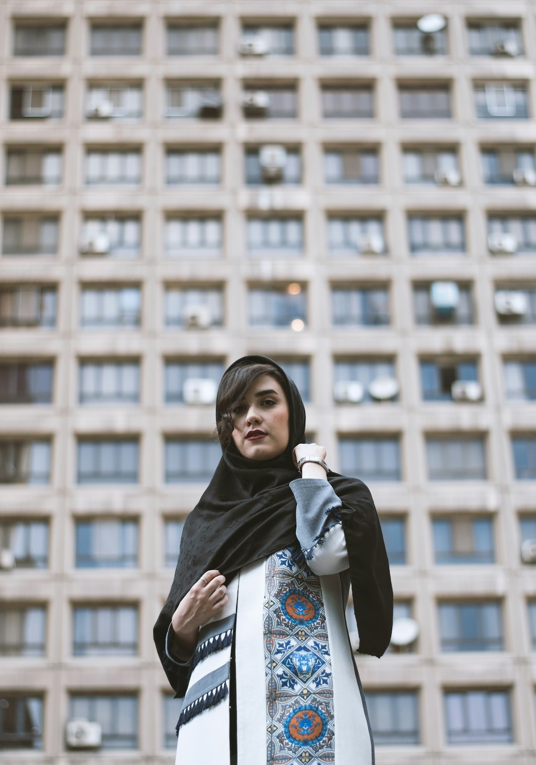 woman in black hijab standing near brown wall