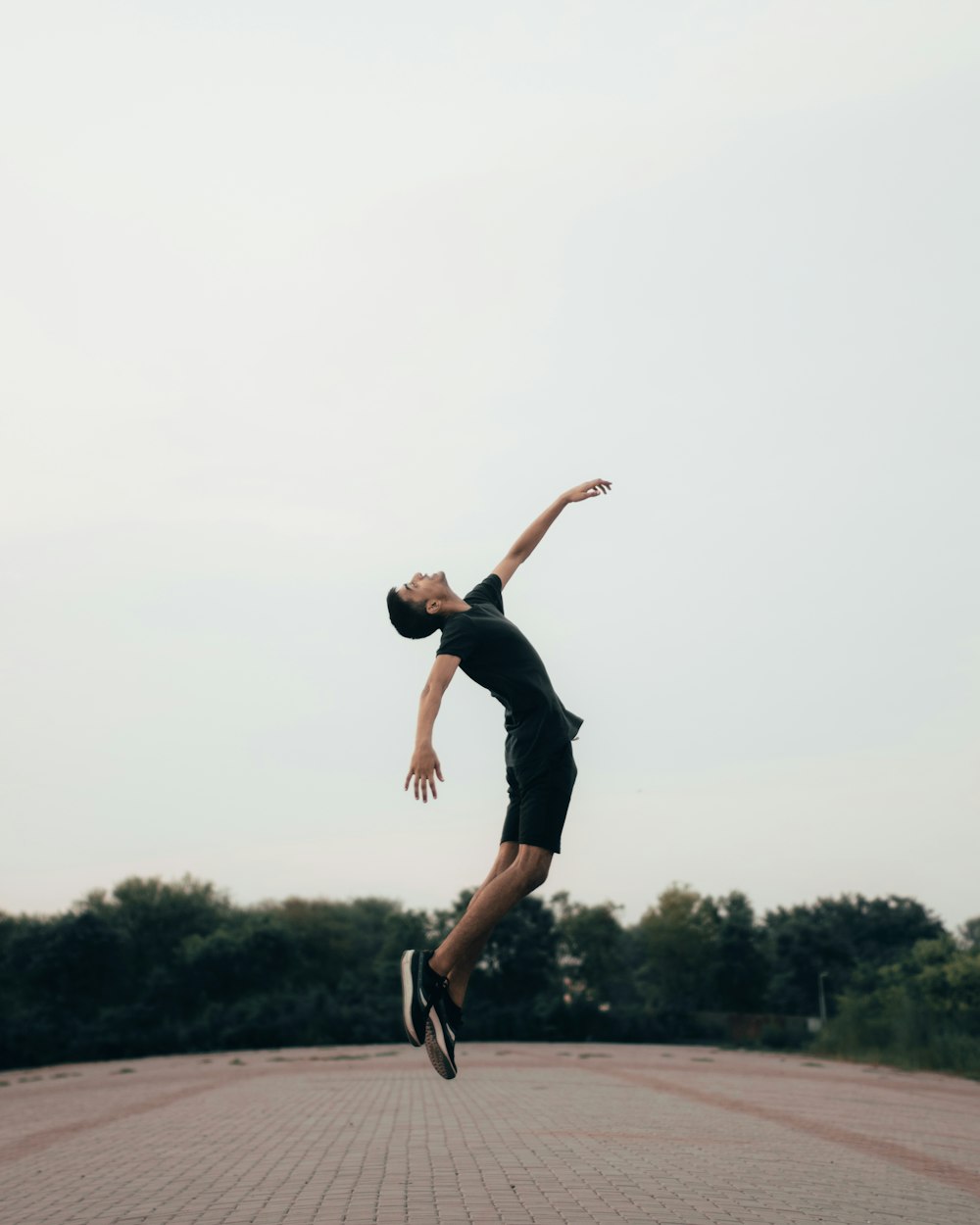 man in black tank top and shorts jumping on mid air during daytime