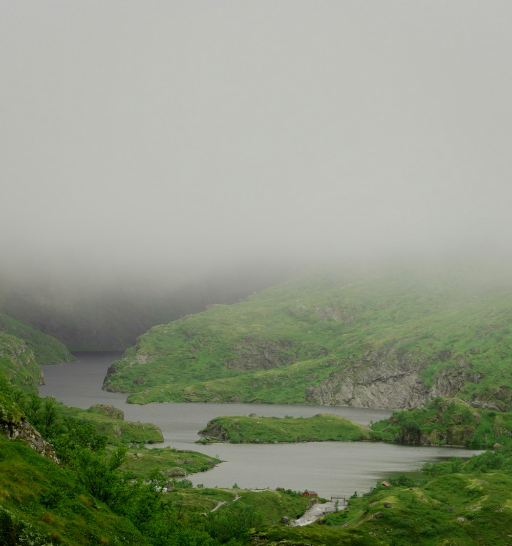 green mountains and river during foggy day