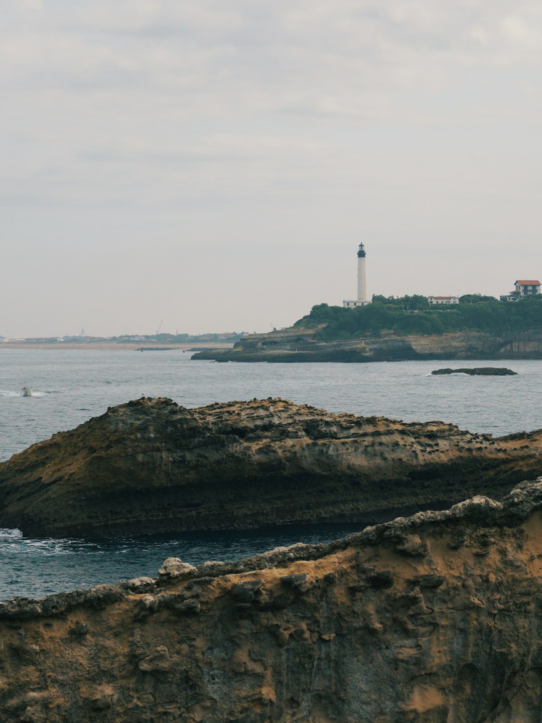 white lighthouse on brown rock formation near body of water during daytime