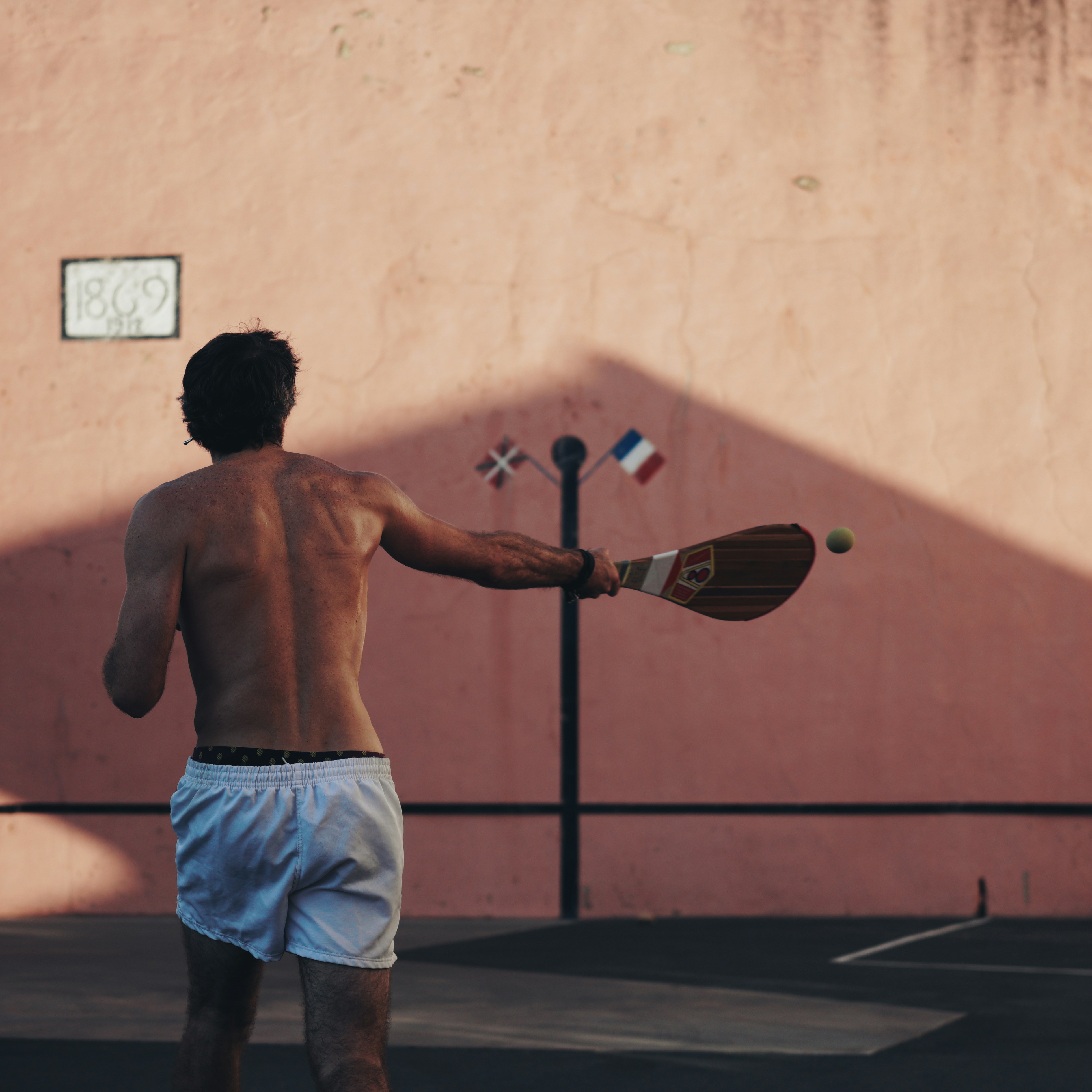 man in blue shorts holding red and black basketball racket
