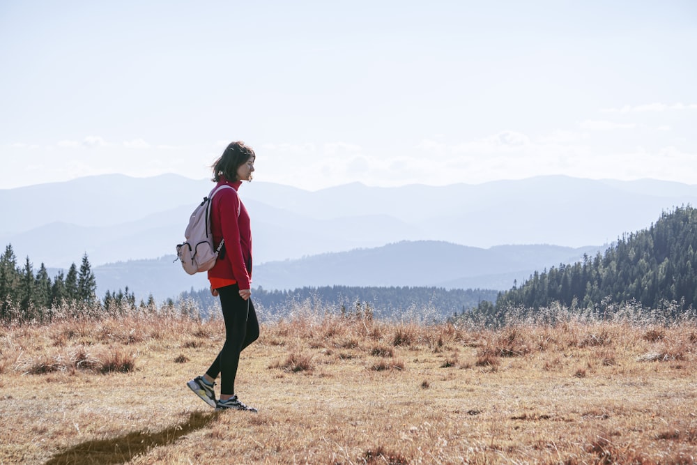 a man with a backpack walking across a dry grass covered field