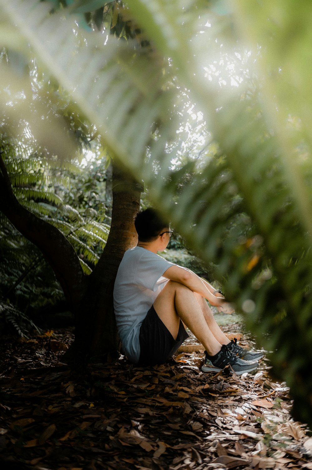 a man sitting on the ground next to a tree