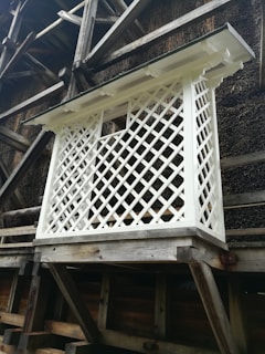 Decorative wooden lattice air conditioner barrier installed on a sunny wall