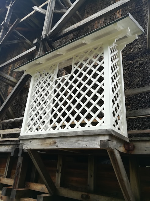Decorative wooden lattice air conditioner barrier installed on a sunny wall