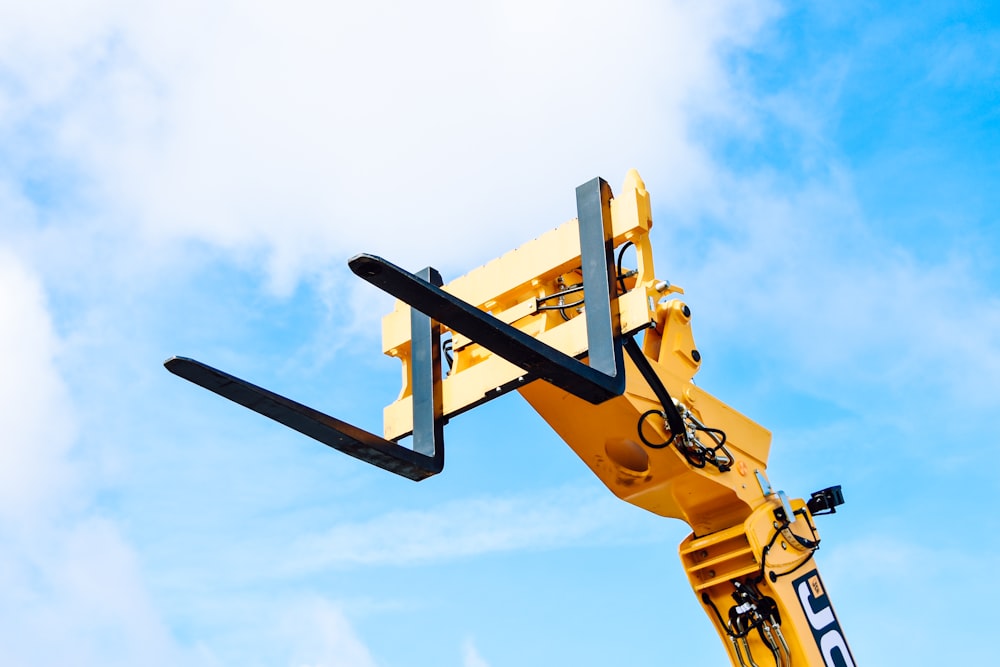 yellow and black crane under white clouds and blue sky during daytime