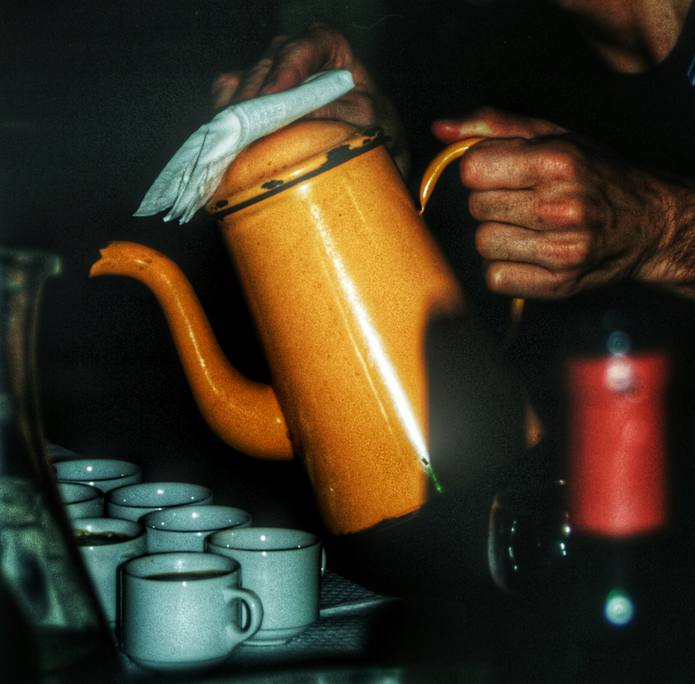 person holding orange and white ceramic teapot