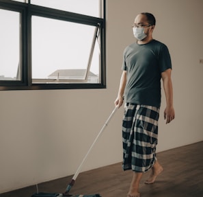 a man with a face mask is cleaning the floor