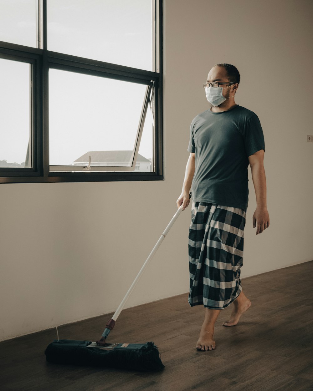 Un hombre con una máscara facial está limpiando el piso