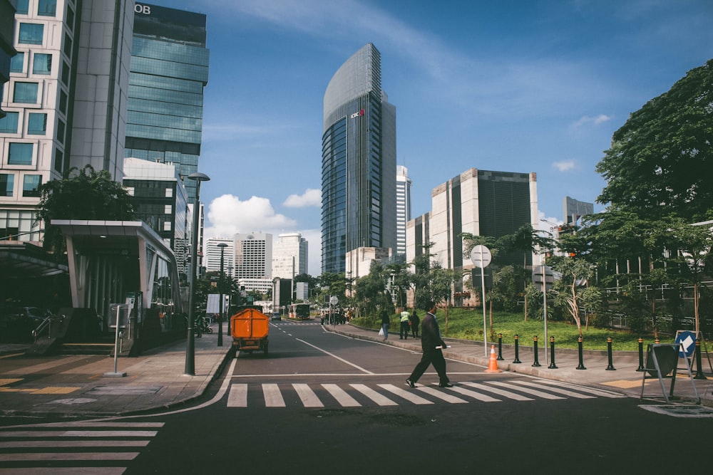 a man walking across a cross walk in a city