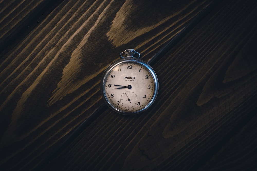 a pocket watch sitting on top of a wooden table