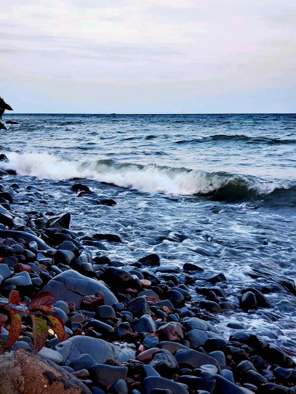 a person standing on a rocky beach next to the ocean