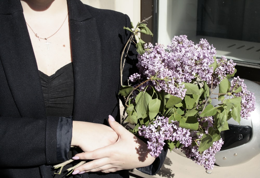 a woman holding a bouquet of purple flowers