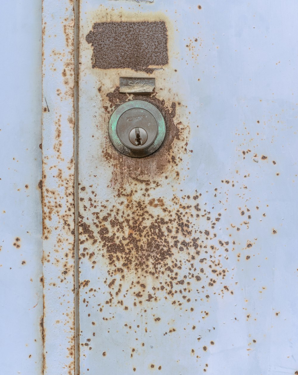 a rusted metal door with a button on it
