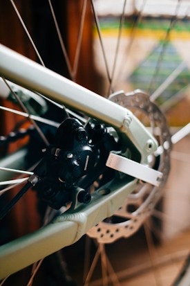 Close-up view of a bicycle's disc brake system, showcasing the rotor and caliper. The metallic and mechanical components are in sharp focus, highlighting the intricate design and engineering details.