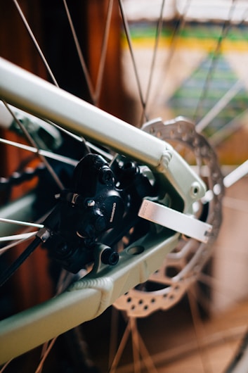 Close-up view of a bicycle's disc brake system, showcasing the rotor and caliper. The metallic and mechanical components are in sharp focus, highlighting the intricate design and engineering details.