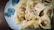 A plate of dumplings is arranged on a decorative dish with floral patterns. The dumplings have a smooth, glossy texture and appear freshly cooked, with steam visible rising from them.