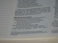 A close-up view of a page in a book, likely religious or historical in nature, detailing the descendants of Levi. The page includes numbered verses and footnotes at the bottom.