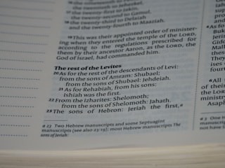 A close-up view of a page in a book, likely religious or historical in nature, detailing the descendants of Levi. The page includes numbered verses and footnotes at the bottom.