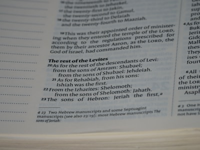 A close-up view of a page in a book, likely religious or historical in nature, detailing the descendants of Levi. The page includes numbered verses and footnotes at the bottom.
