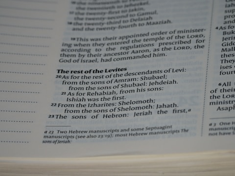 A close-up view of a page in a book, likely religious or historical in nature, detailing the descendants of Levi. The page includes numbered verses and footnotes at the bottom.