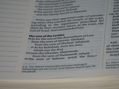 A close-up view of a page in a book, likely religious or historical in nature, detailing the descendants of Levi. The page includes numbered verses and footnotes at the bottom.