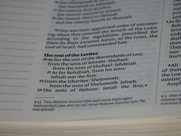 A close-up view of a page in a book, likely religious or historical in nature, detailing the descendants of Levi. The page includes numbered verses and footnotes at the bottom.