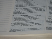 A close-up view of a page in a book, likely religious or historical in nature, detailing the descendants of Levi. The page includes numbered verses and footnotes at the bottom.