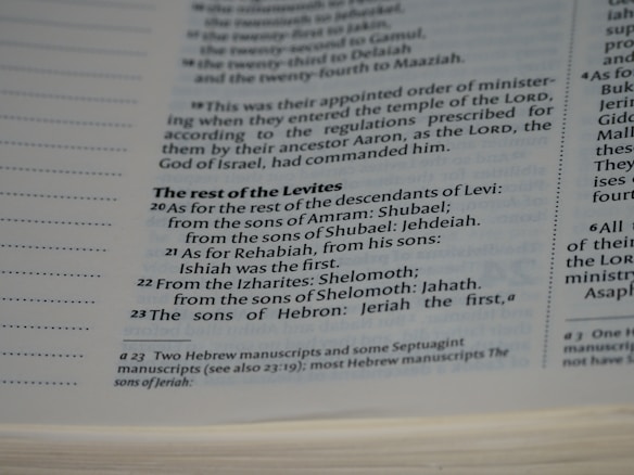 A close-up view of a page in a book, likely religious or historical in nature, detailing the descendants of Levi. The page includes numbered verses and footnotes at the bottom.