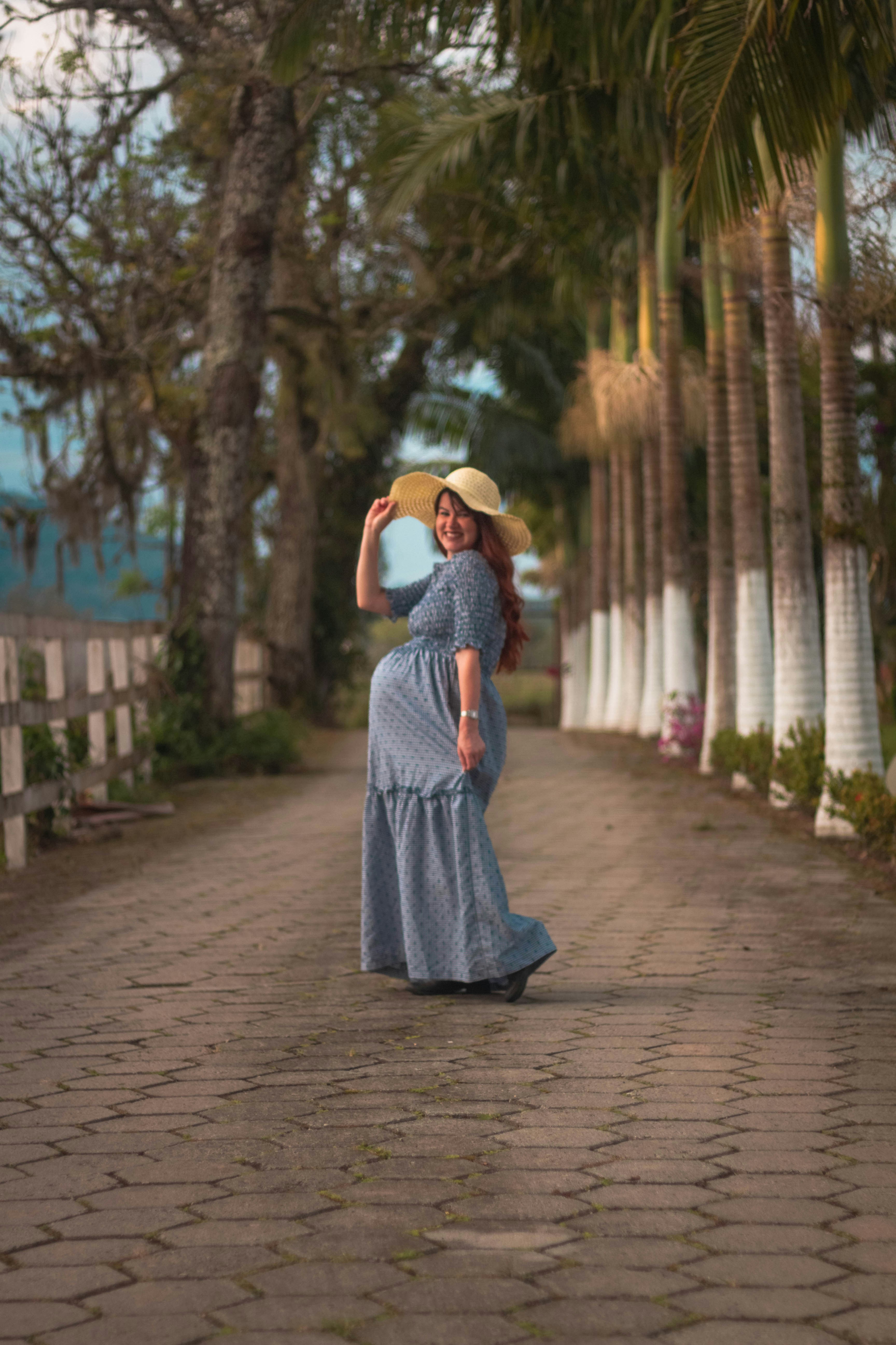A woman in a blue dress and hat walking down a street photo – Free ...
