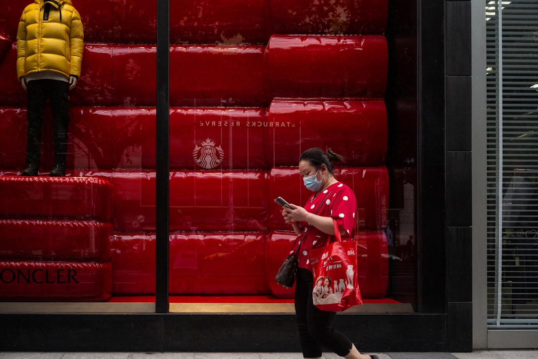 girl in red and white floral shirt and black pants sitting on red metal fence during