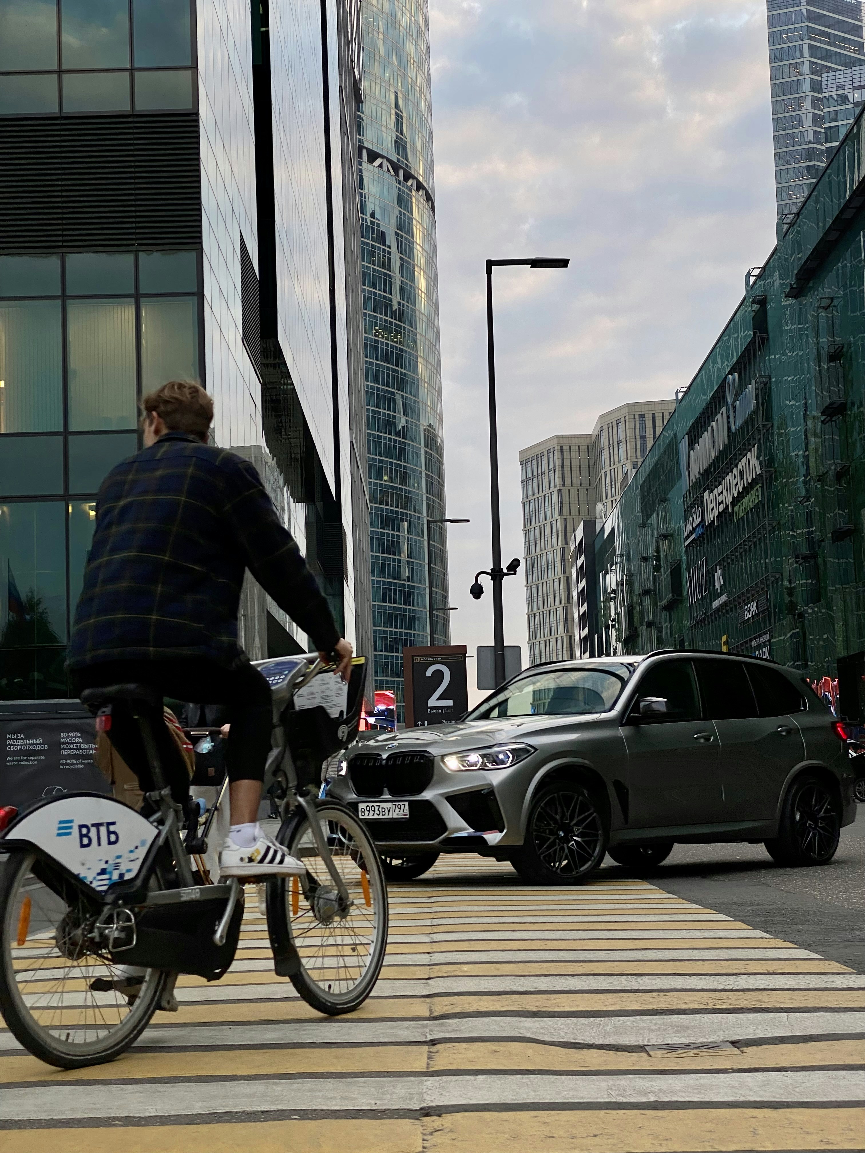 高層ビルの隣の通りを自転車で走る男