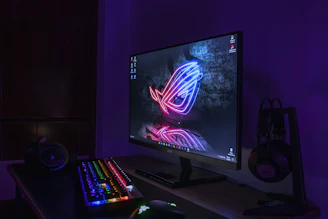a computer monitor and keyboard lit up in the dark