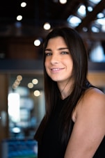 a woman in a black dress smiling at the camera