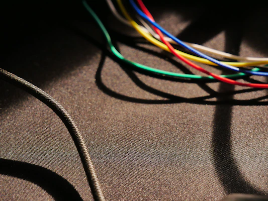 Coiled bundles of colorful wires and cables neatly arranged on a deep blue surface