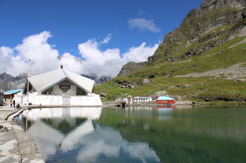 Hemkund Sahib near body of water and green mountain under blue sky during daytime