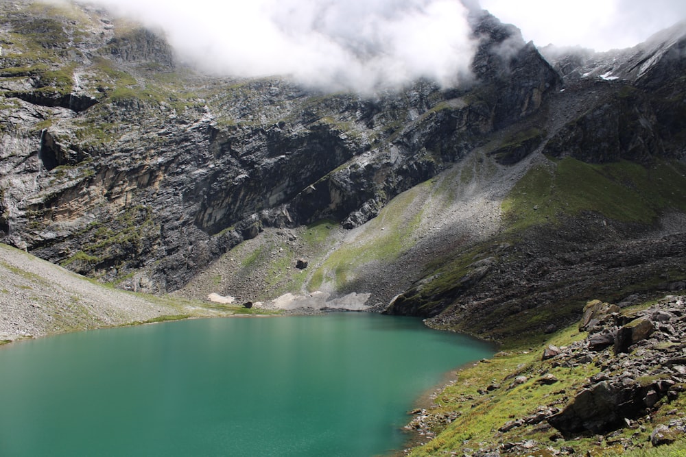 green lake in the middle of green and gray mountains