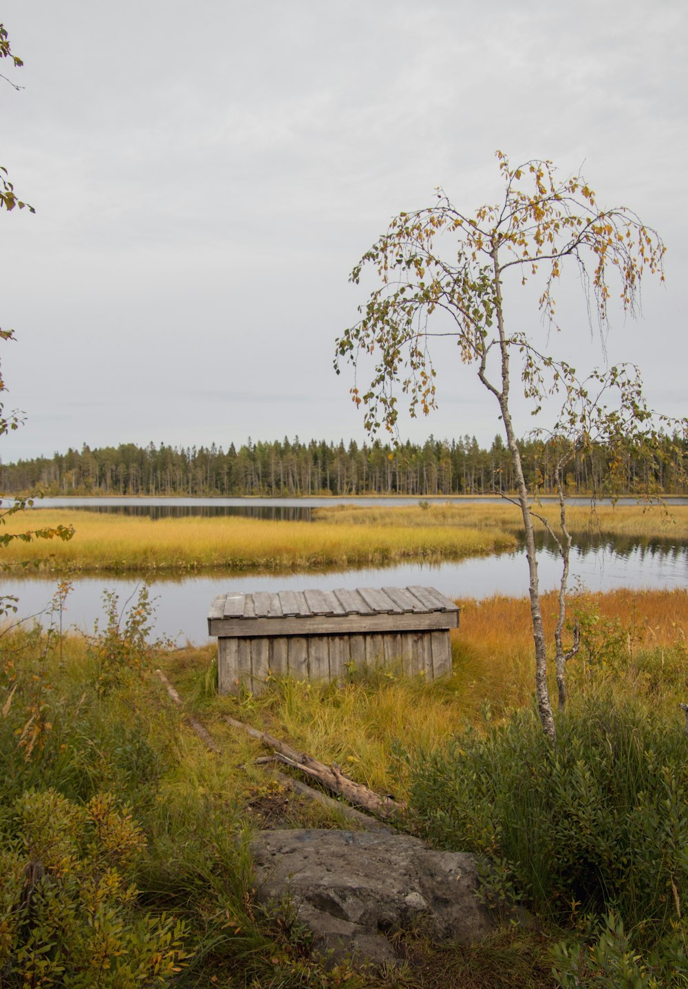 a small wooden outhouse sitting in the middle of a field