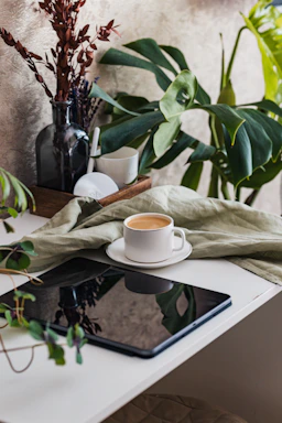 A cozy kitchen scene showing a person checking out groceries on a tablet with a cup of coffee nearby.