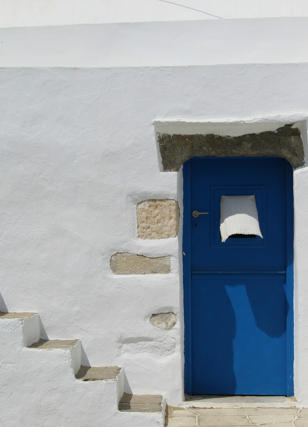 porta di legno blu su parete di cemento bianco